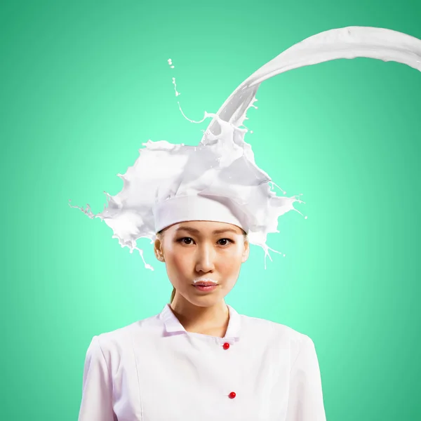 Asian female cook against milk splashes — Stock Photo, Image