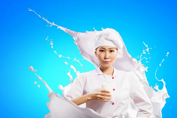 Asian female cook against milk splashes — Stock Photo, Image