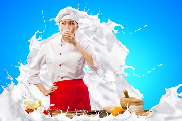 Asian female cook against milk splashes — Stock Photo, Image