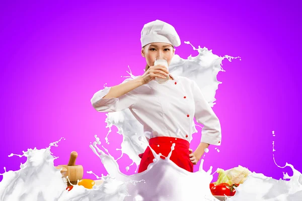 Asian female cook against milk splashes — Stock Photo, Image