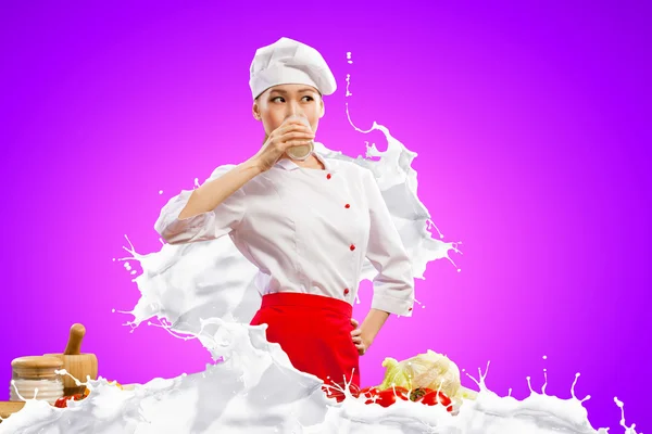 Asian female cook against milk splashes — Stock Photo, Image