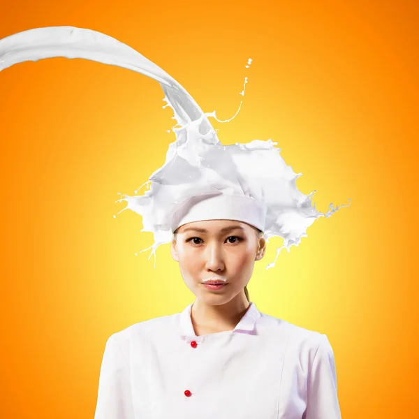 Asian female cook against milk splashes — Stock Photo, Image