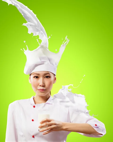 Asian female cook against milk splashes — Stock Photo, Image