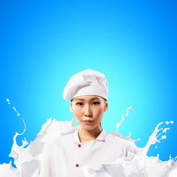 Asian female cook against milk splashes — Stock Photo, Image