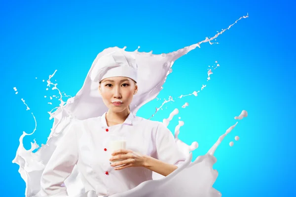 Asian female cook against milk splashes — Stock Photo, Image