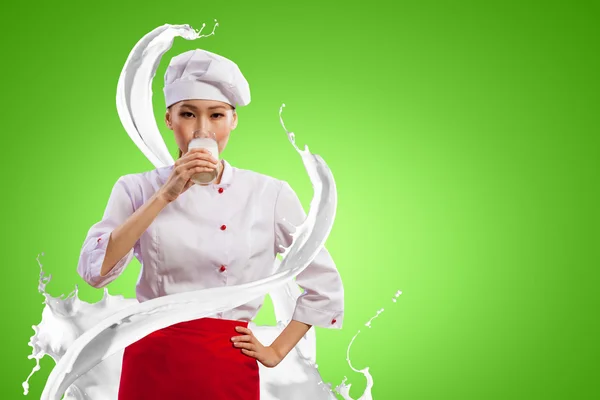 Asian female cook against milk splashes — Stock Photo, Image