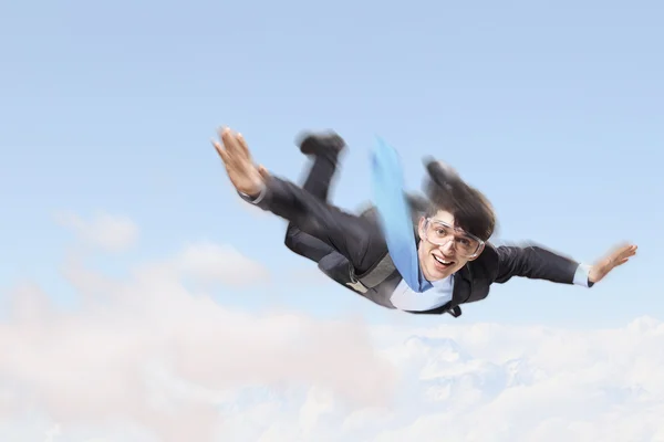 Young businessman flying with parachute on back — Stock Photo, Image