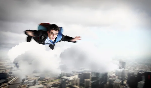 Молодой бизнесмен летит с парашютом на спине — стоковое фото