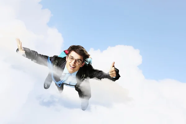 Young businessman flying with parachute on back — Stock Photo, Image