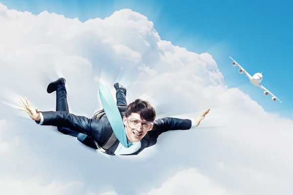 Young businessman flying with parachute on back — Stock Photo, Image