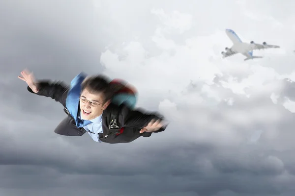 Young businessman flying with parachute on back — Stock Photo, Image