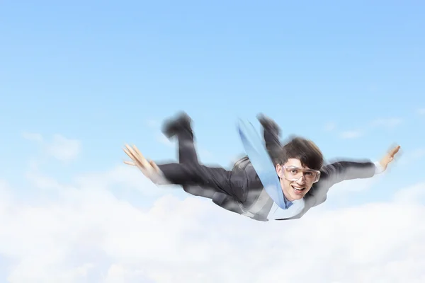 Young businessman flying with parachute on back — Stock Photo, Image