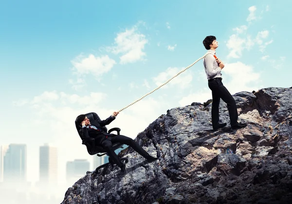 Two businessmen pulling rope atop of mountain — Stock Photo, Image