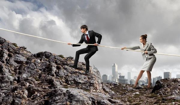 Två affärsmän dra rep på toppen av berget — Stockfoto