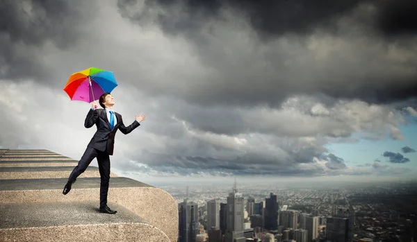 Businessman with umbrella atop of building — Stock Photo, Image