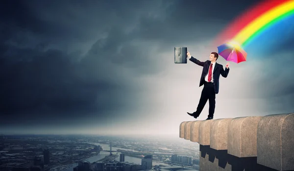 Podnikatel s deštníkem na vrcholu budovy — Stock fotografie