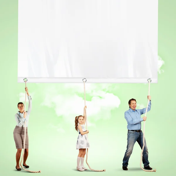 Happy family pulling banner — Stock Photo, Image