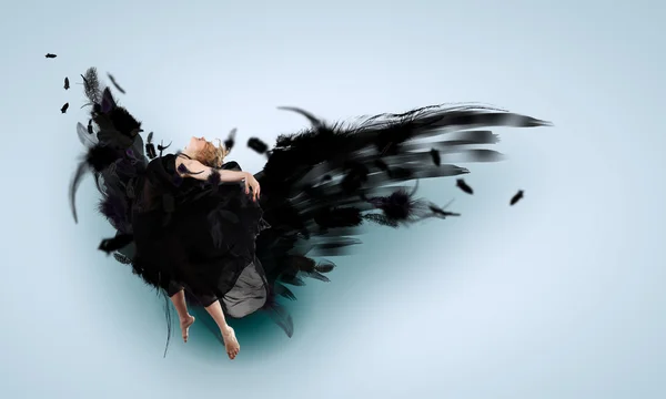 Женщина, плавающая на тёмных крыльях — стоковое фото