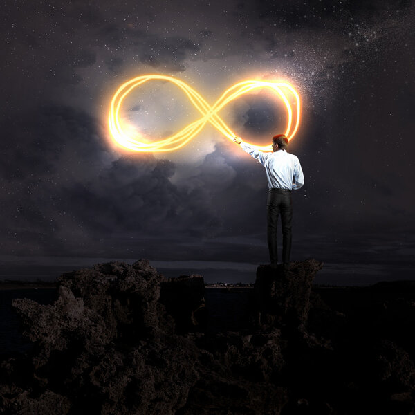 Image of businessman drawing infinity sign in the sky
