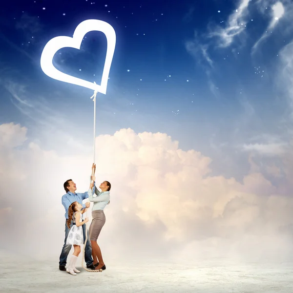 Family pulling rope with a heart symbol — Stock Photo, Image