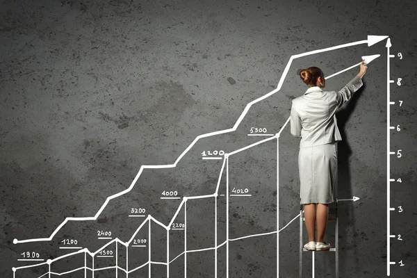 Woman standing on ladder drawing on wall — Stock Photo, Image