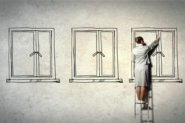 Woman standing on ladder drawing on wall — Stock Photo, Image