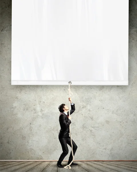 Businessman pulling blank banner — Stock Photo, Image