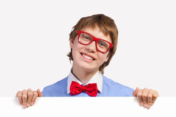 Αγόρι σχολείο σε κόκκινα γυαλιά κρατώντας λευκό τετράγωνο — Stockfoto