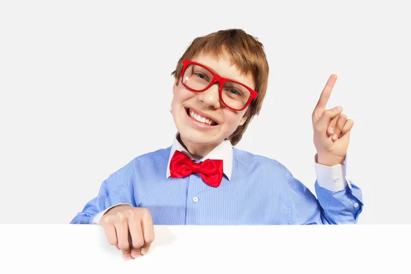 Αγόρι σχολείο σε κόκκινα γυαλιά κρατώντας λευκό τετράγωνο — Stockfoto