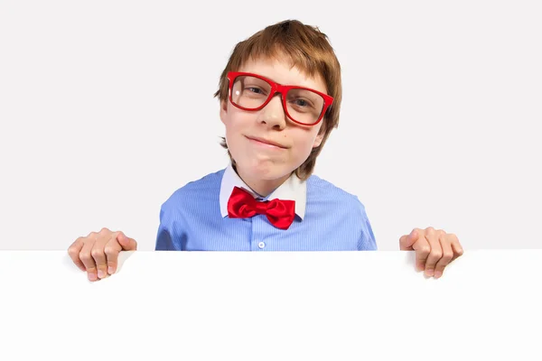 Menino da escola em óculos vermelhos segurando quadrado branco — Fotografia de Stock