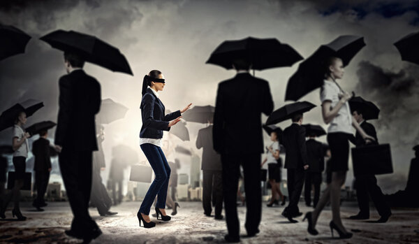 Businesswoman in blindfold among group of