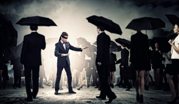 Businessman in blindfold among group of