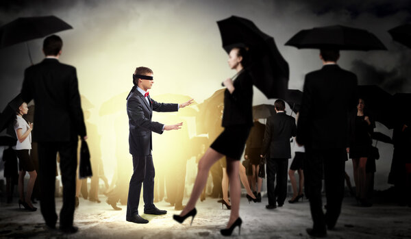 Businessman in blindfold among group of