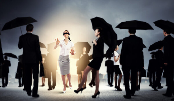 Businesswoman in blindfold among group of