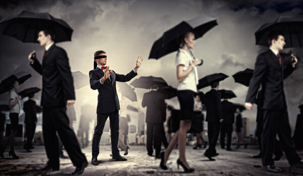 Businessman in blindfold among group of