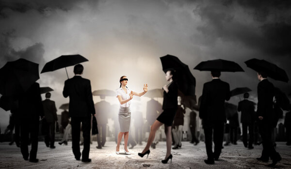 Businesswoman in blindfold among group of