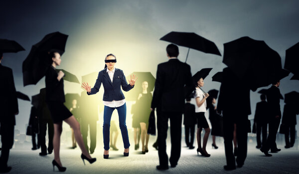 Businesswoman in blindfold among group of