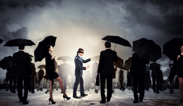 Businessman in blindfold among group of