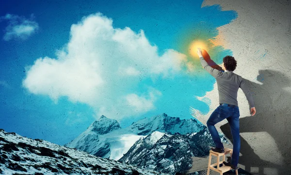 Young man drawing a cloudy blue sky — Stock Photo, Image