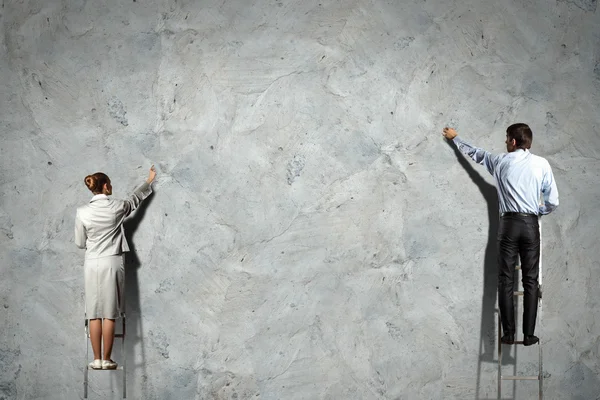 Geschäftsleute malen Diagramme an die Wand — Stockfoto