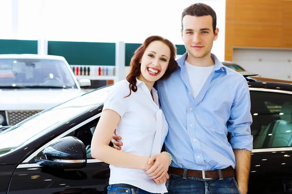 Молодая счастливая пара в автосалоне — стоковое фото