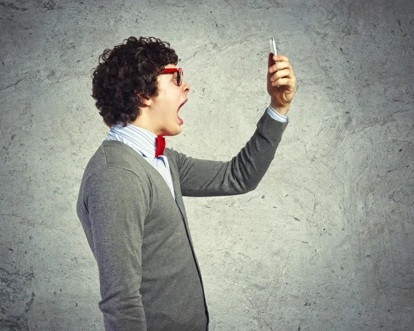 Молодой человек кричит на свой мобильный телефон — стоковое фото