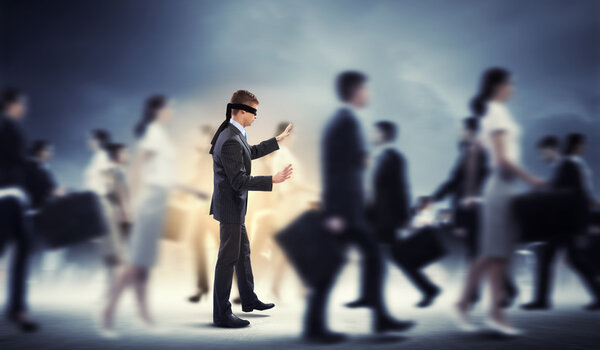 Businessman in blindfold among group of people
