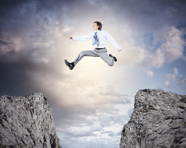 Businessman jumping over gap
