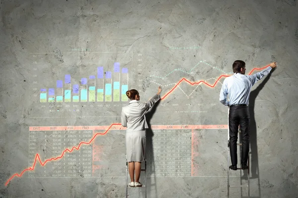 Businesspeople drawing diagrams on wall — Stock Photo, Image