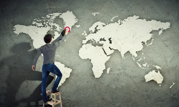 Young man drawing a map on the wall — Stock Photo, Image