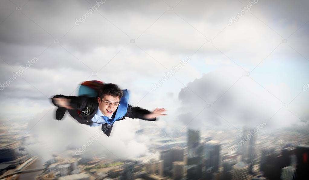 Young businessman flying with parachute on back
