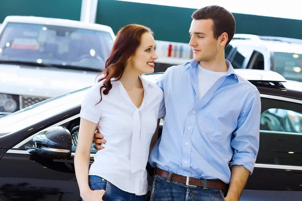 Young happy couple at car salon — Stock Photo, Image