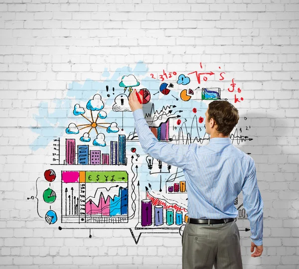 Businessman drawing sketches on wall — Stock Photo, Image