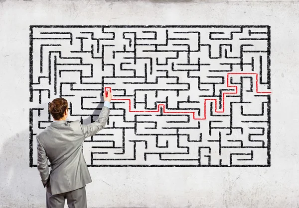 Businessman solving labyrinth problem — Stock Photo, Image